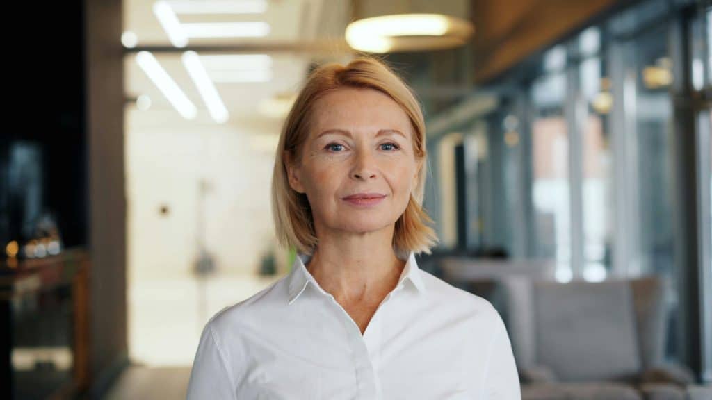 Confident senior woman in a modern office setting, smiling at the camera.